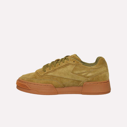 The Reebok Club C LTD Shoes feature tan suede with olive green accents and laces, a chunky textured light brown rubber sole, and are displayed in a left side profile on a white background—a lifestyle classic.