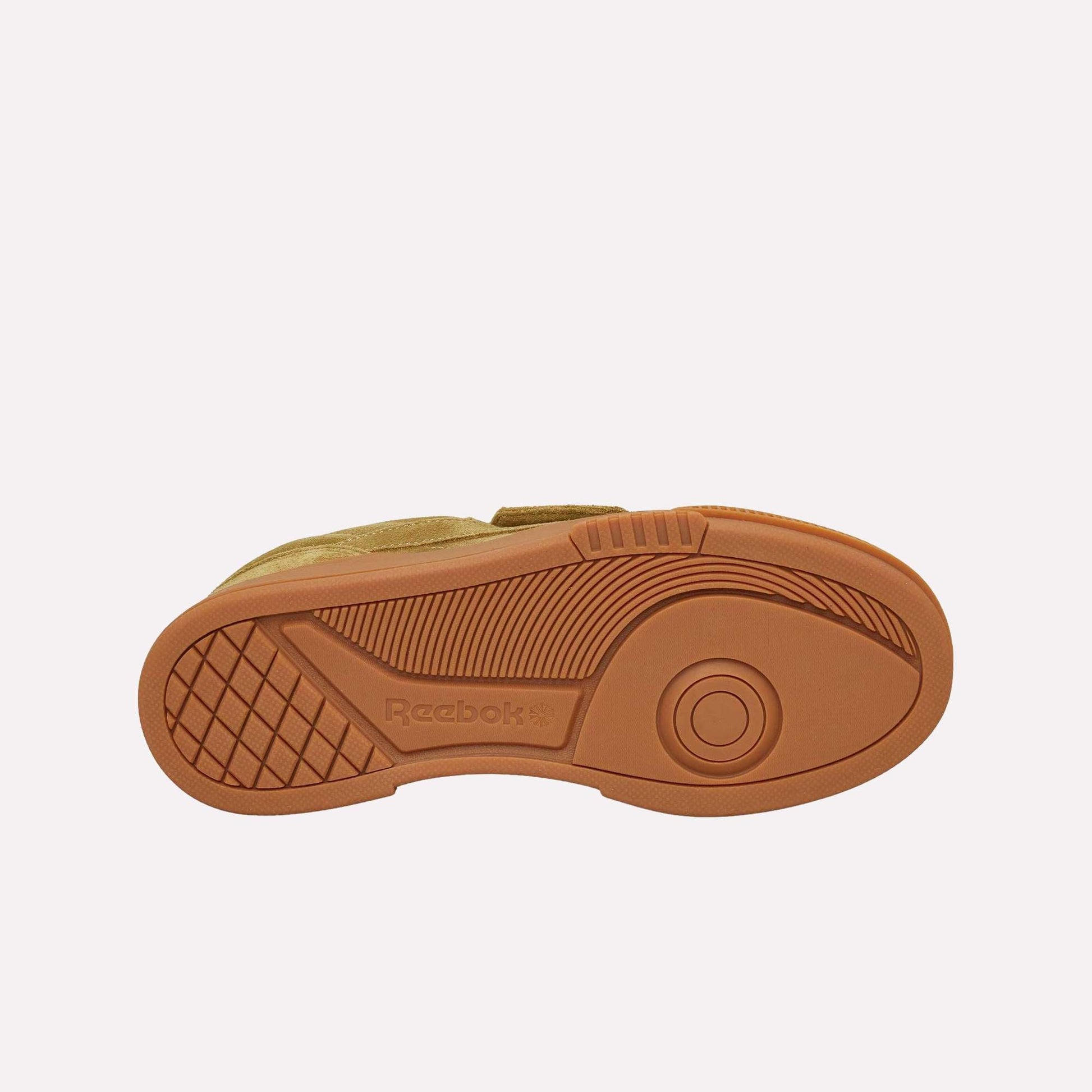 The image shows the bottom view of the Reebok Club C LTD Shoes in tan, featuring a textured rubber sole with a circular tread pattern and the Reebok logo near the arch—a true lifestyle classic.