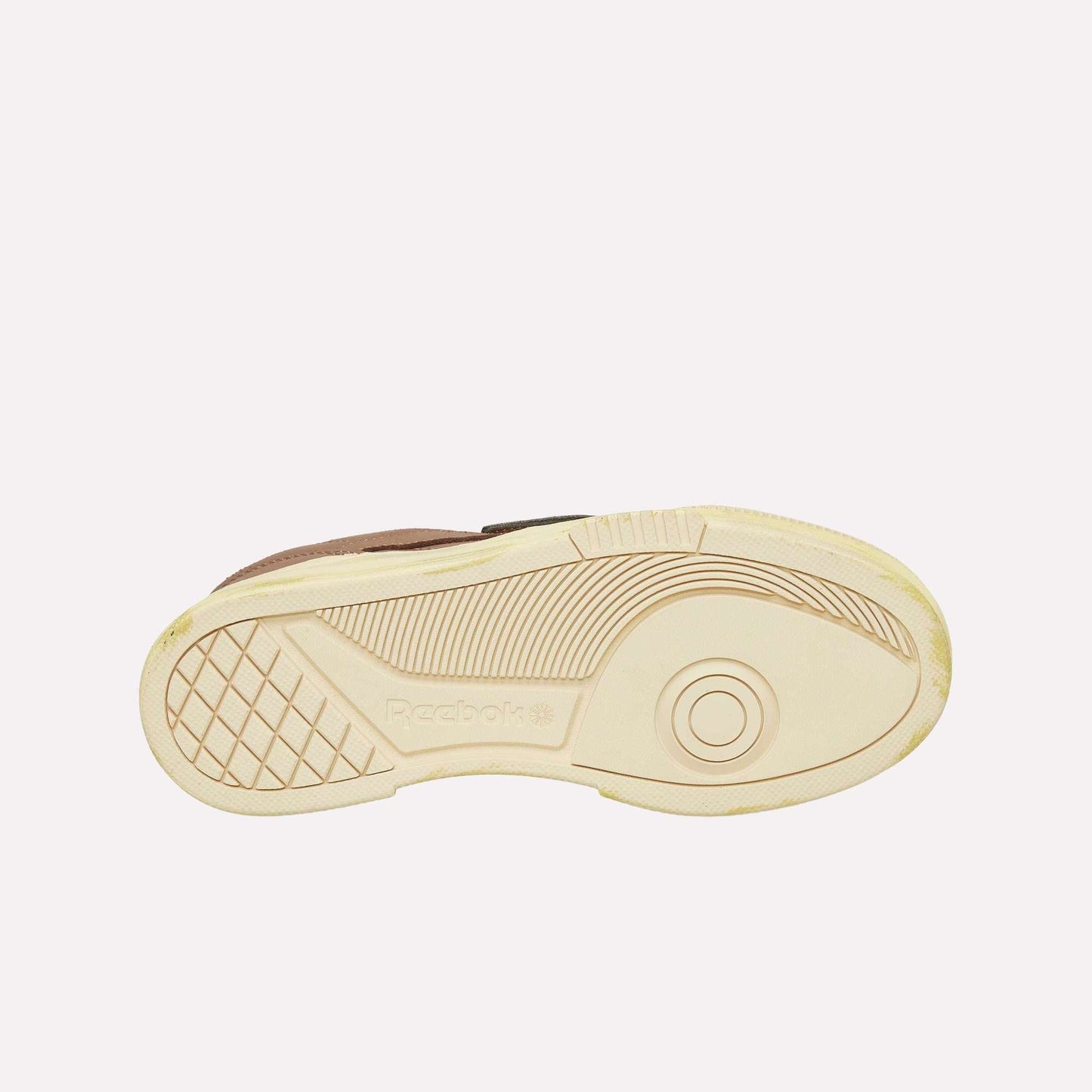The image features the beige sole of a Reebok Club C LTD Shoe against a white background, showcasing its tread pattern and the embossed Reebok logo—a true lifestyle classic.