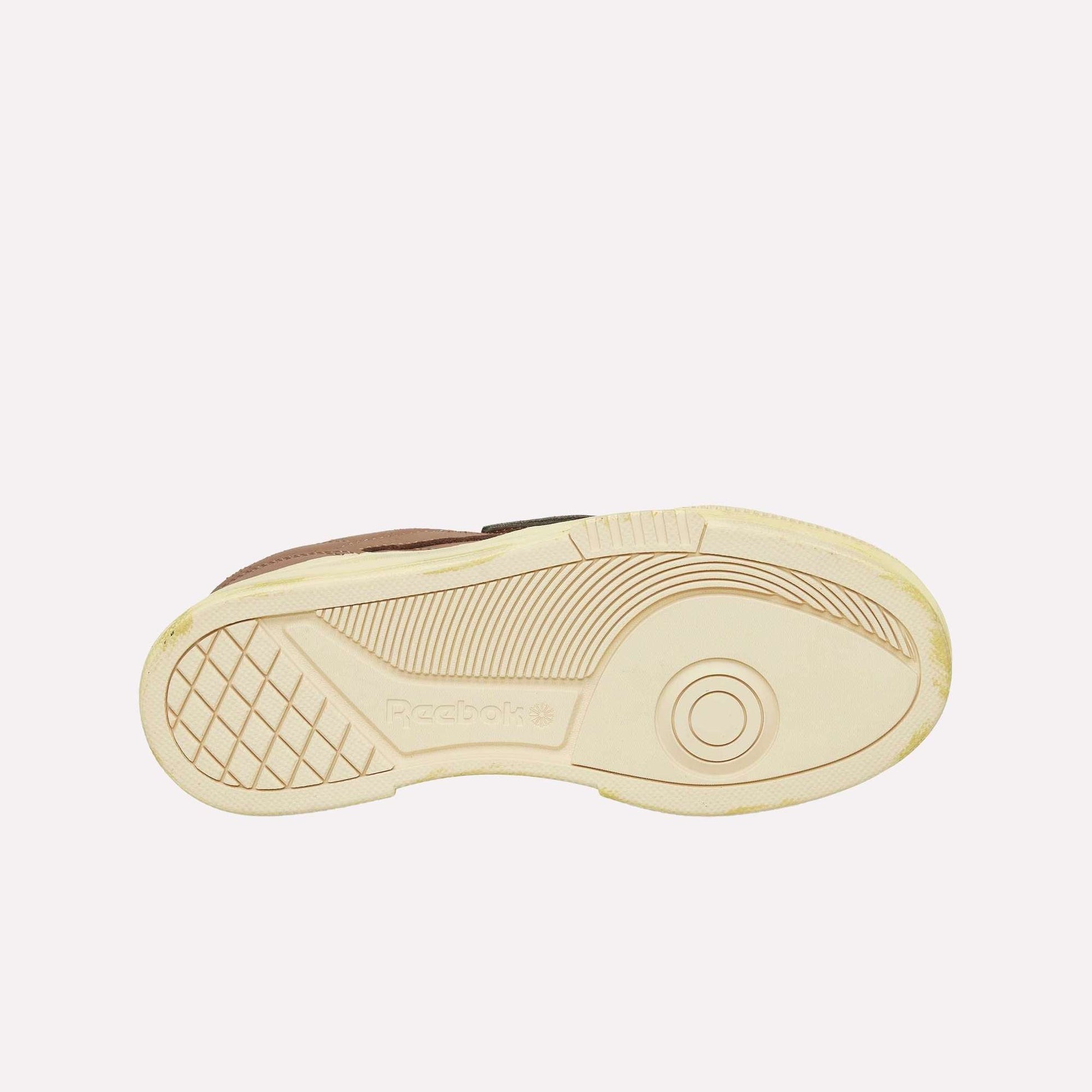 The image features the beige sole of a Reebok Club C LTD Shoe against a white background, showcasing its tread pattern and the embossed Reebok logo—a true lifestyle classic.