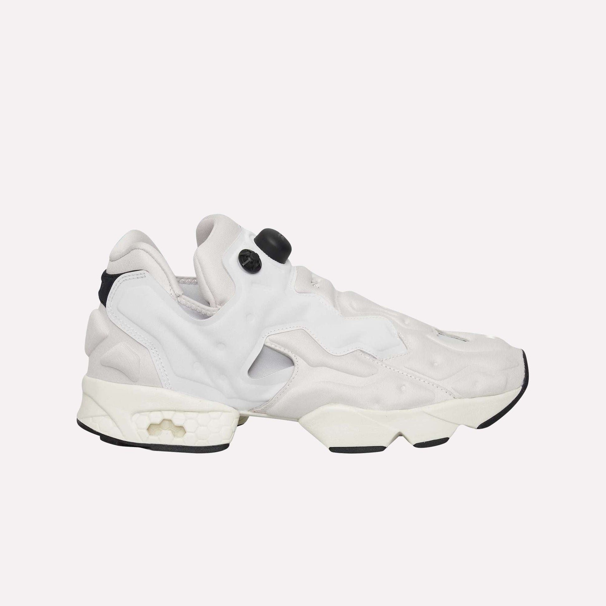 The Reebok Instapump Sliver Shoes are white and light gray sneakers with a chunky sole and unique cutout design, featuring Hexalite cushioning for comfort, displayed from the side on a light blue background.