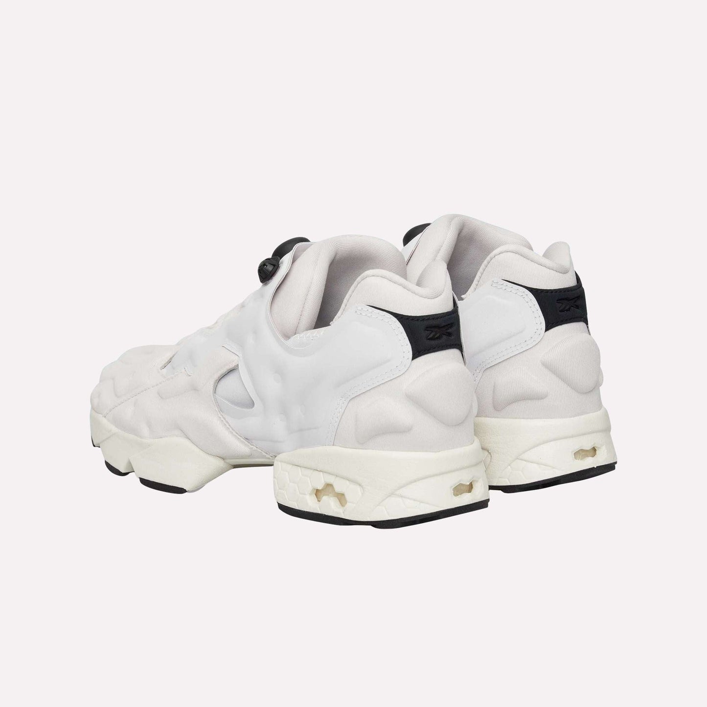 The Reebok Instapump Sliver Shoes, white with chunky soles, black heel accents, and cutout details featuring Hexalite cushioning, are shown from the back on a light blue background.