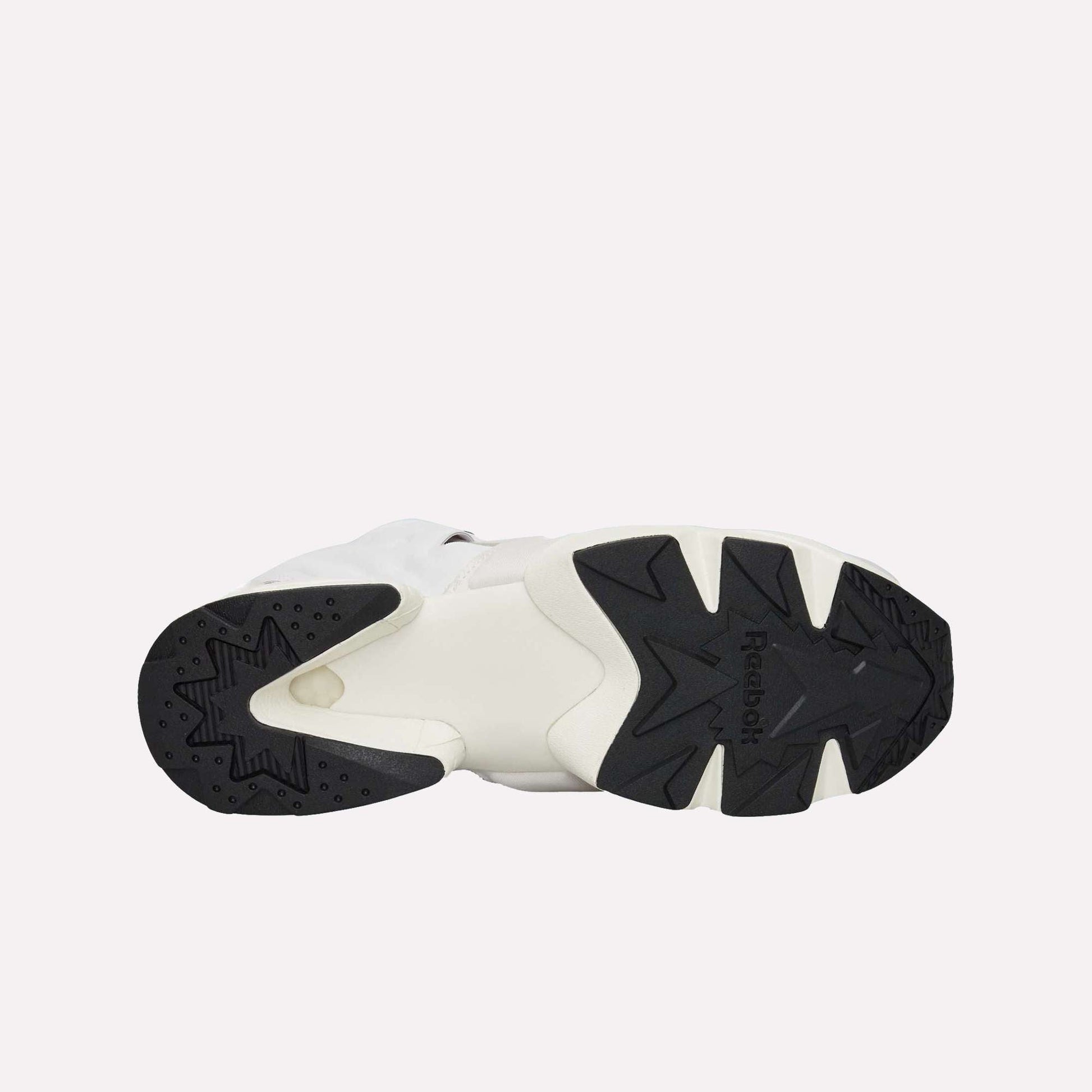 The image displays the sole of Reebok Instapump Sliver Shoes, with a mainly black and white geometric tread pattern for grip and Hexalite cushioning, set against a light blue background.