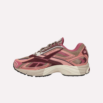 The Reebok Premier Road Ultra Shoes, shown from the side on a white background, are running sneakers in pink, maroon, and tan with mesh and suede uppers, a dual-density midsole, textured sole, and layered details.