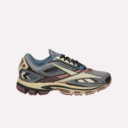 The Reebok Premier Road Ultra Shoes are shown in a left side profile on a light blue background, featuring a multicolored design with gray, blue, burgundy, cream, and black accents and a dual-density midsole for enhanced comfort.