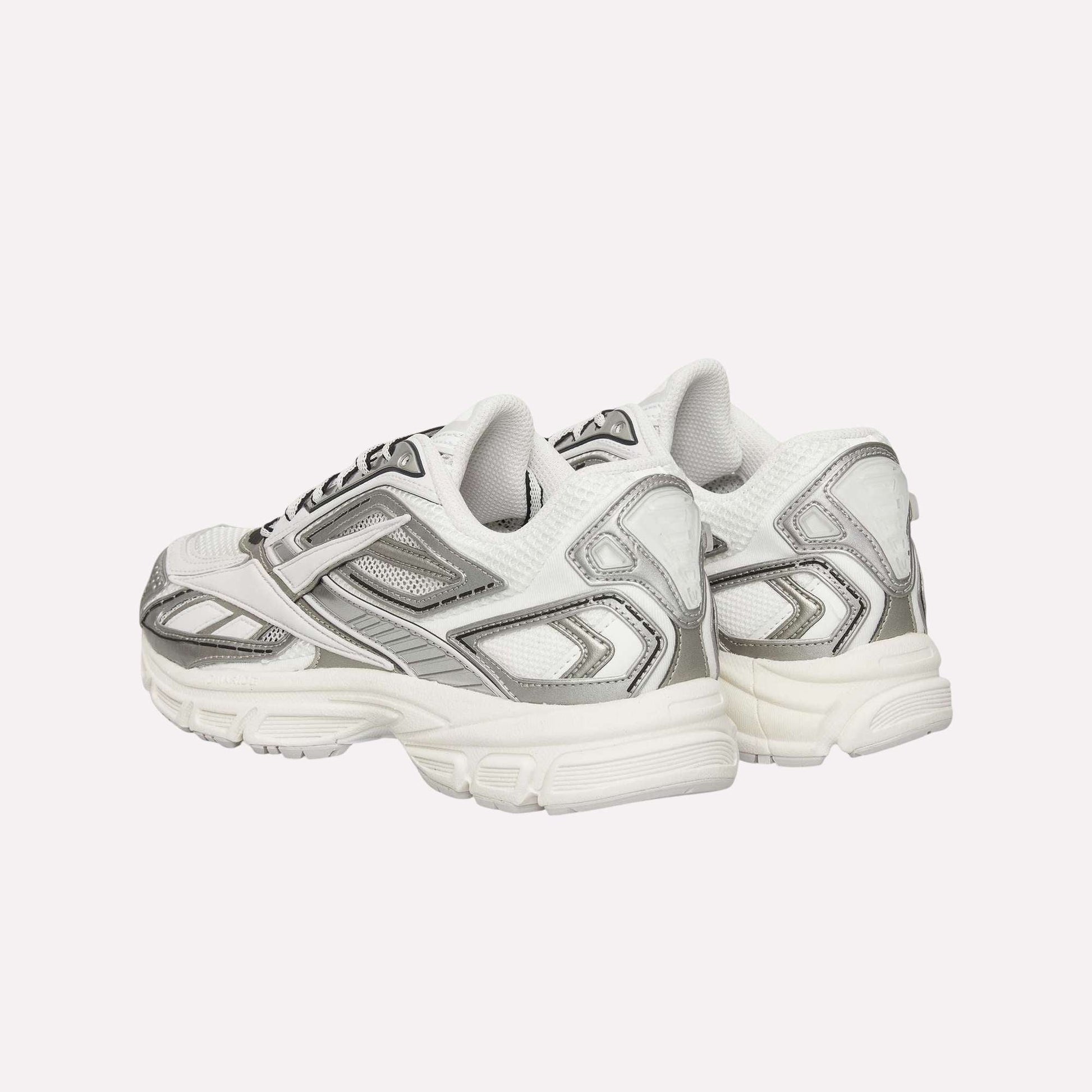 A pair of Reebok Premier Road Ultra Shoes in white and silver are placed back-to-back, highlighting chunky soles, layered mesh and synthetic panels, plus a dual-density midsole designed for comfort.