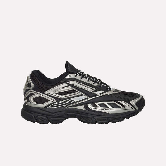 The Reebok Premier Road Ultra Shoes feature a black mesh upper with metallic silver accents, black laces, angular patterns, a chunky dual-density rubber sole, and boast a modern, sporty look.