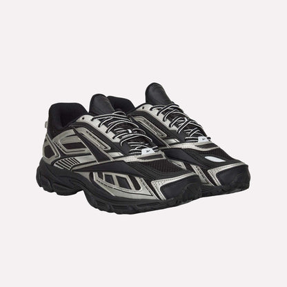 A pair of Reebok Premier Road Ultra Shoes in black and silver, featuring a chunky sole, mesh panels, dual-density midsole, and patterned overlays, displayed side by side angled slightly to the right.