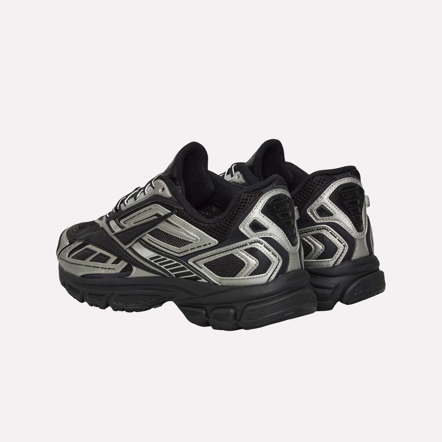 The Reebok Premier Road Ultra Shoes are chunky athletic running sneakers with silver, black, and grey panels, seen from back and side angles, featuring a dual-density midsole, thick soles, and mesh detailing.