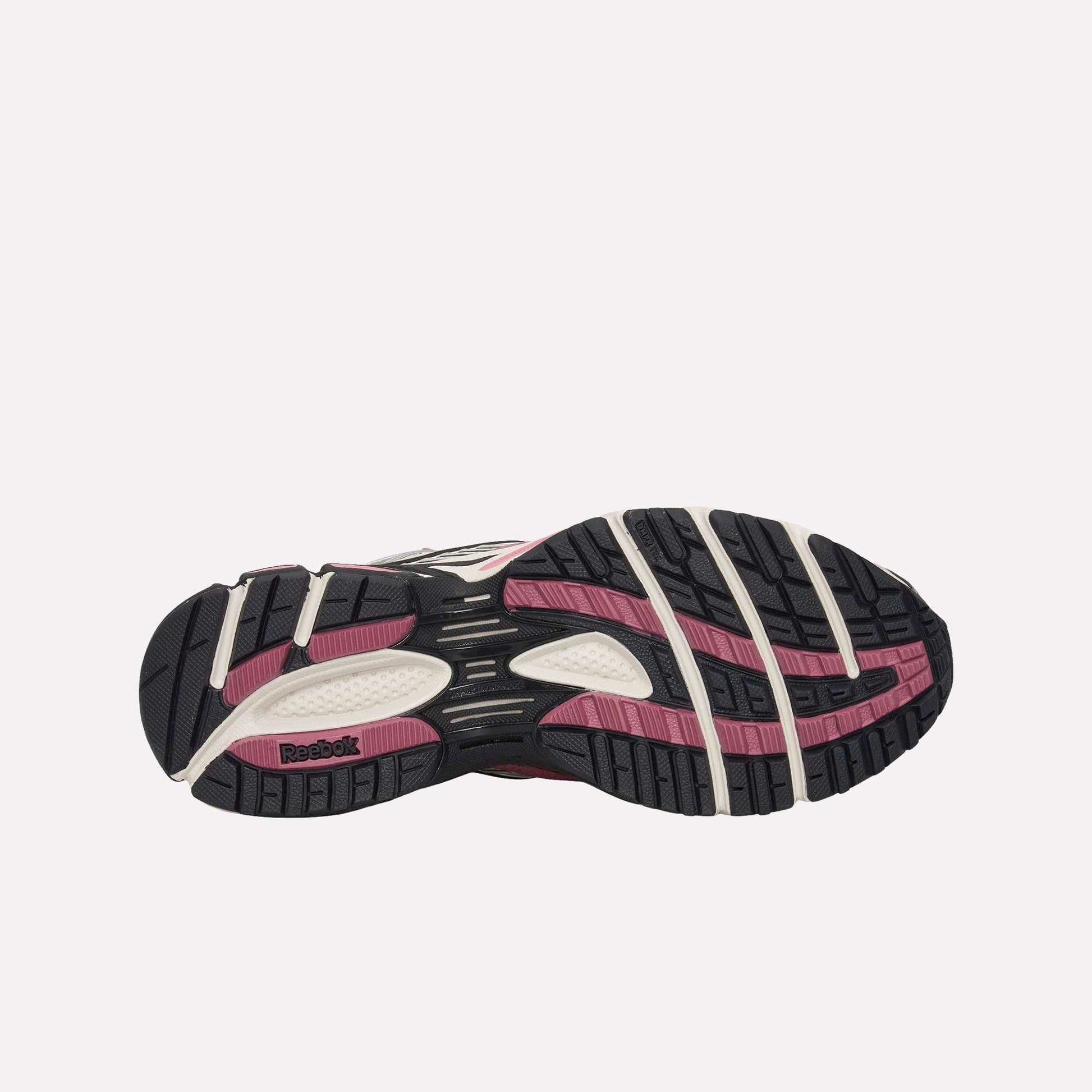 Bottom view of the Reebok Premier Road Ultra Shoes, featuring a textured black, pink, and white rubber outsole with grooves and a Reebok logo by the heel—engineered for comfort with a dual-density midsole.