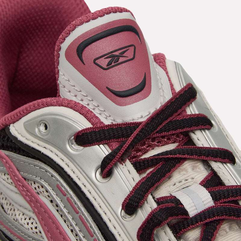 Close-up of the Reebok Premier Road Ultra Shoes in pink, white, and gray, highlighting the laces, mesh upper texture, dual-density midsole, and Reebok logo on the tongue.