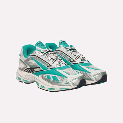 A pair of Reebok Premier Road Ultra Shoes in white and turquoise, with black and silver accents and a dual-density midsole, displayed on a light blue background.