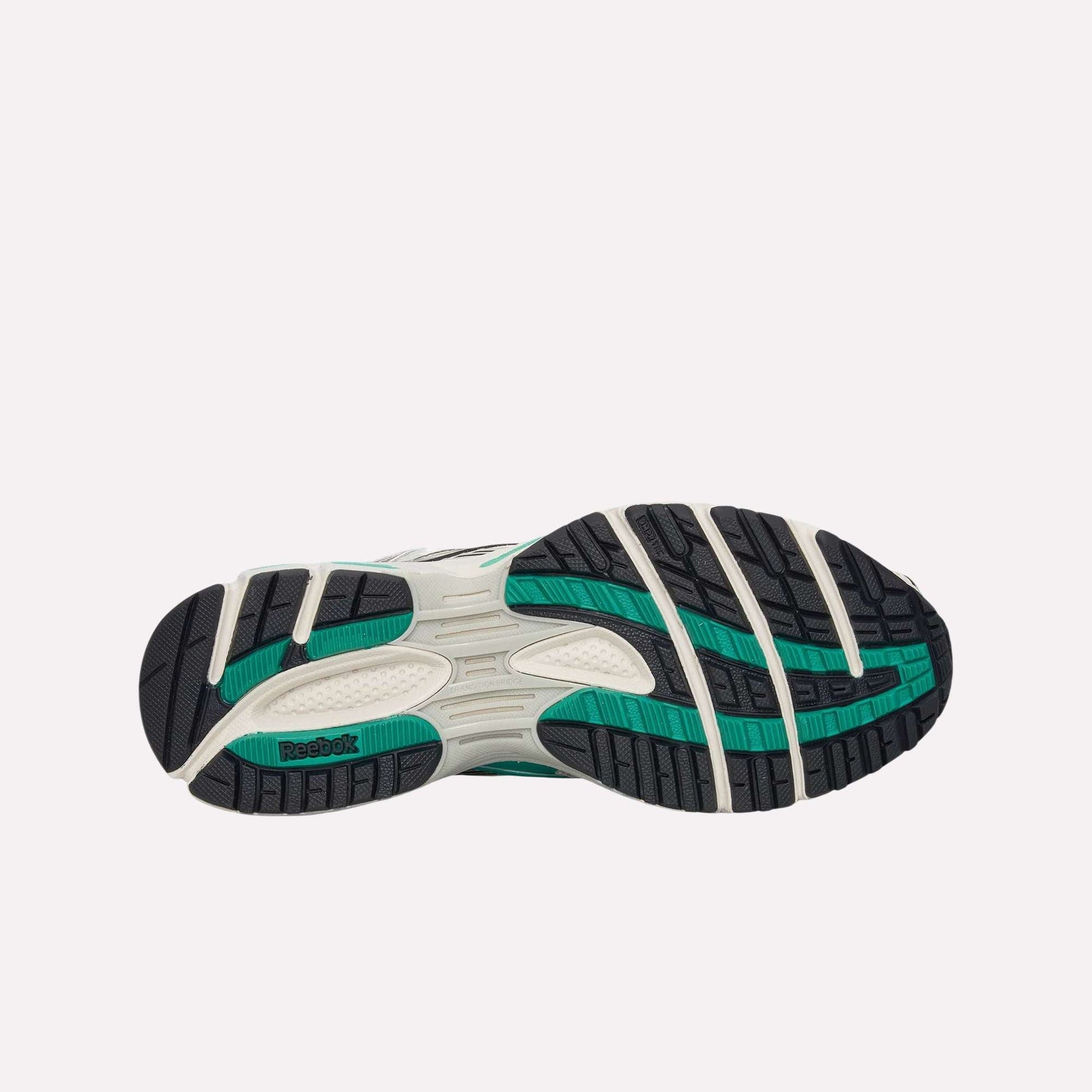 The image displays the sole of the Reebok Premier Road Ultra Shoes, featuring a white base with black and teal tread patterns and Reebok branding, set against a light blue background.