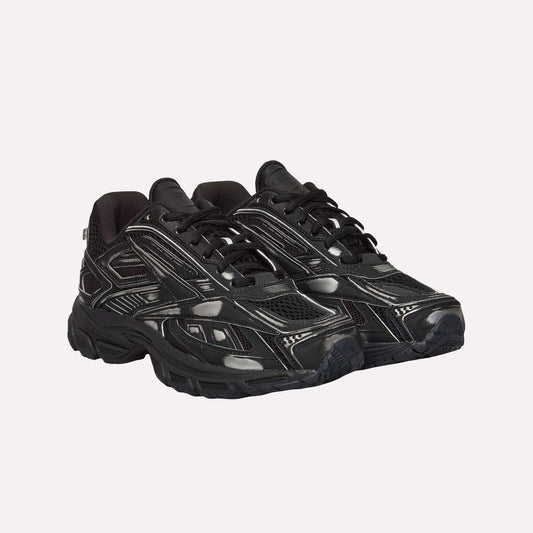 A pair of black Reebok Premier Road Ultra Shoes with textured soles, mesh panels, shiny synthetic overlays, white stitching accents, and a dual-density midsole are shown side by side on a white background.