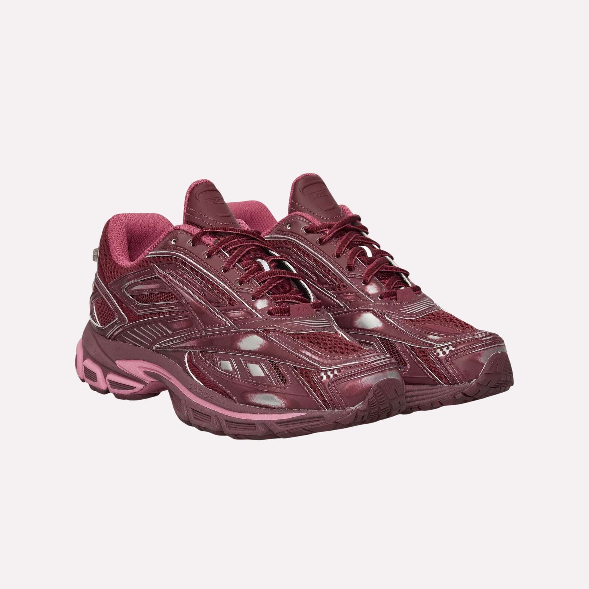 A pair of maroon Reebok Premier Road Ultra Shoes with a glossy finish and pink accents, thick soles, and textured details for comfort and stability, shown side by side on a white background.