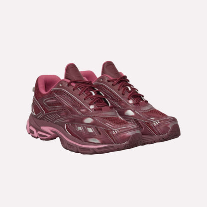 A pair of maroon Reebok Premier Road Ultra Shoes with a glossy finish and pink accents, thick soles, and textured details for comfort and stability, shown side by side on a white background.