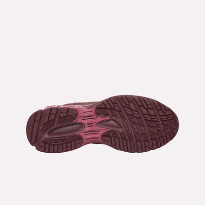 The image displays the bottom view of Reebok Premier Road Ultra Shoes, highlighting a maroon and pink treaded sole with textured grooves for comfort and stability, plus the Reebok logo near the heel.