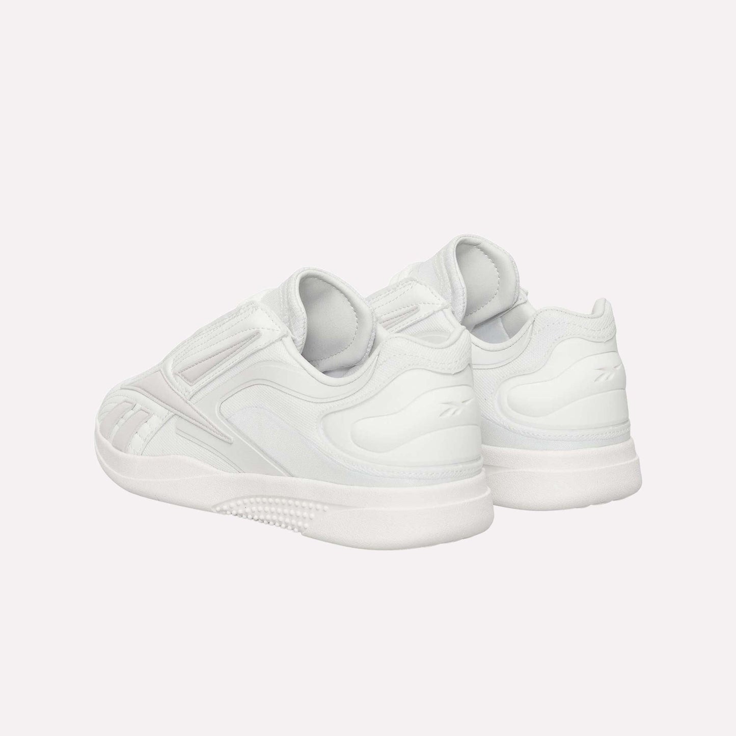 The Reebok Hammer Pro LTD Shoes are shown from the back and side, boasting a sleek minimal design, durable textured rubber soles, and subtle stitching details.