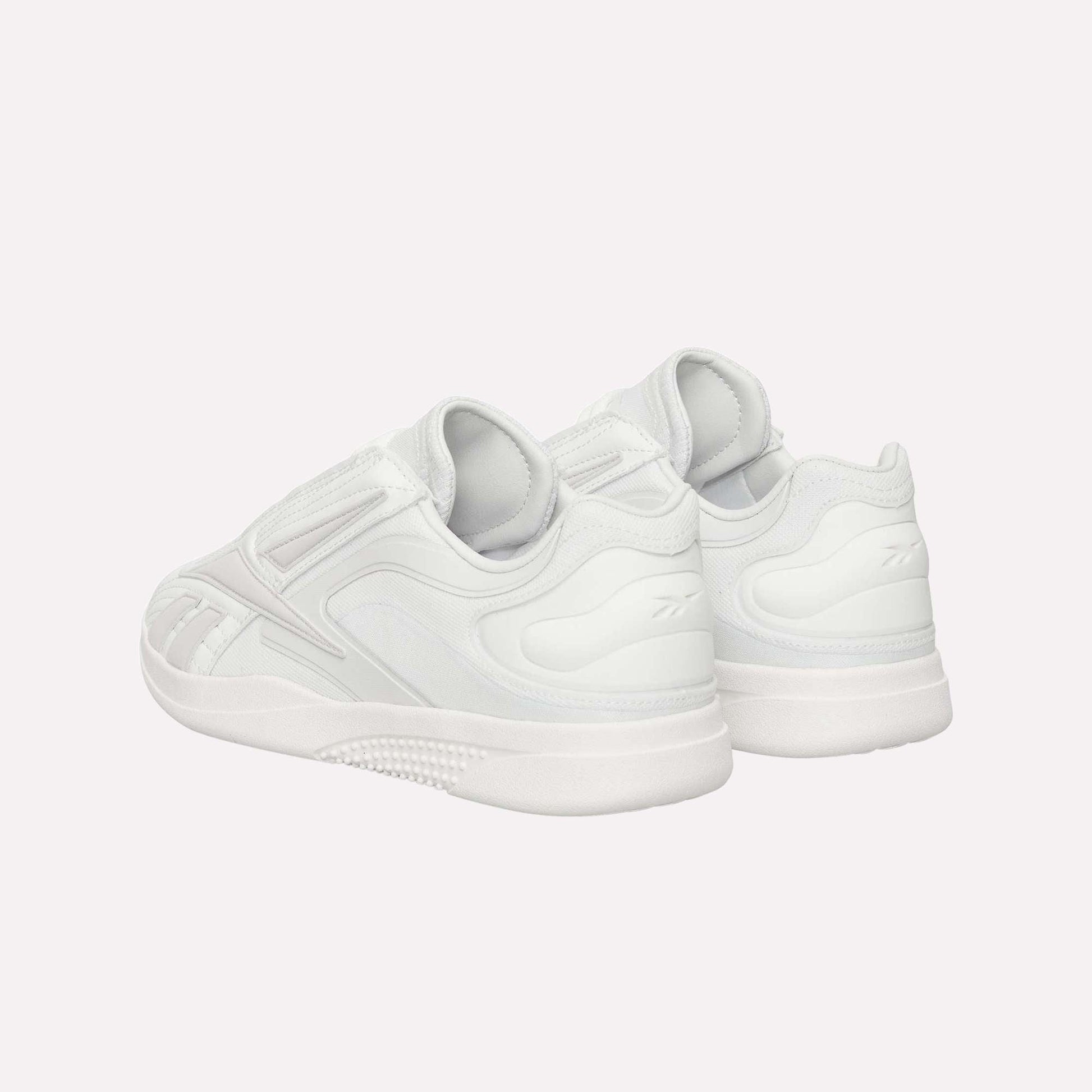 The Reebok Hammer Pro LTD Shoes are shown from the back and side, boasting a sleek minimal design, durable textured rubber soles, and subtle stitching details.