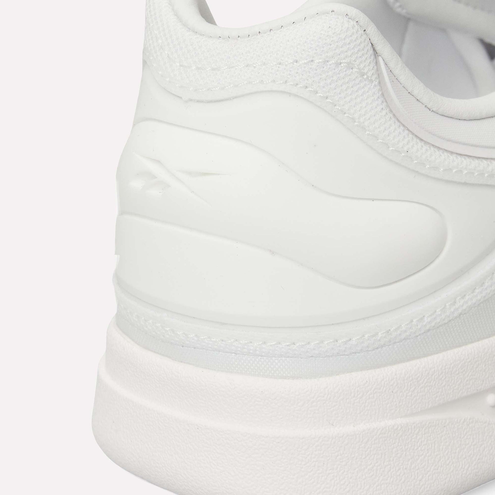 Close-up of the heel and side of Reebok Hammer Pro LTD Shoes with a subtle logo embossed on textured faux leather. Smooth and mesh materials combine with a durable rubber sole for a clean, minimalistic look.