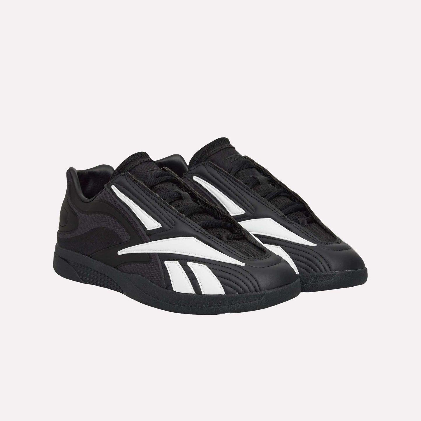 The Reebok Hammer Pro LTD Shoes are black faux leather sneakers with modern, graphic white stripes and a chunky, durable rubber sole, displayed on a white background.