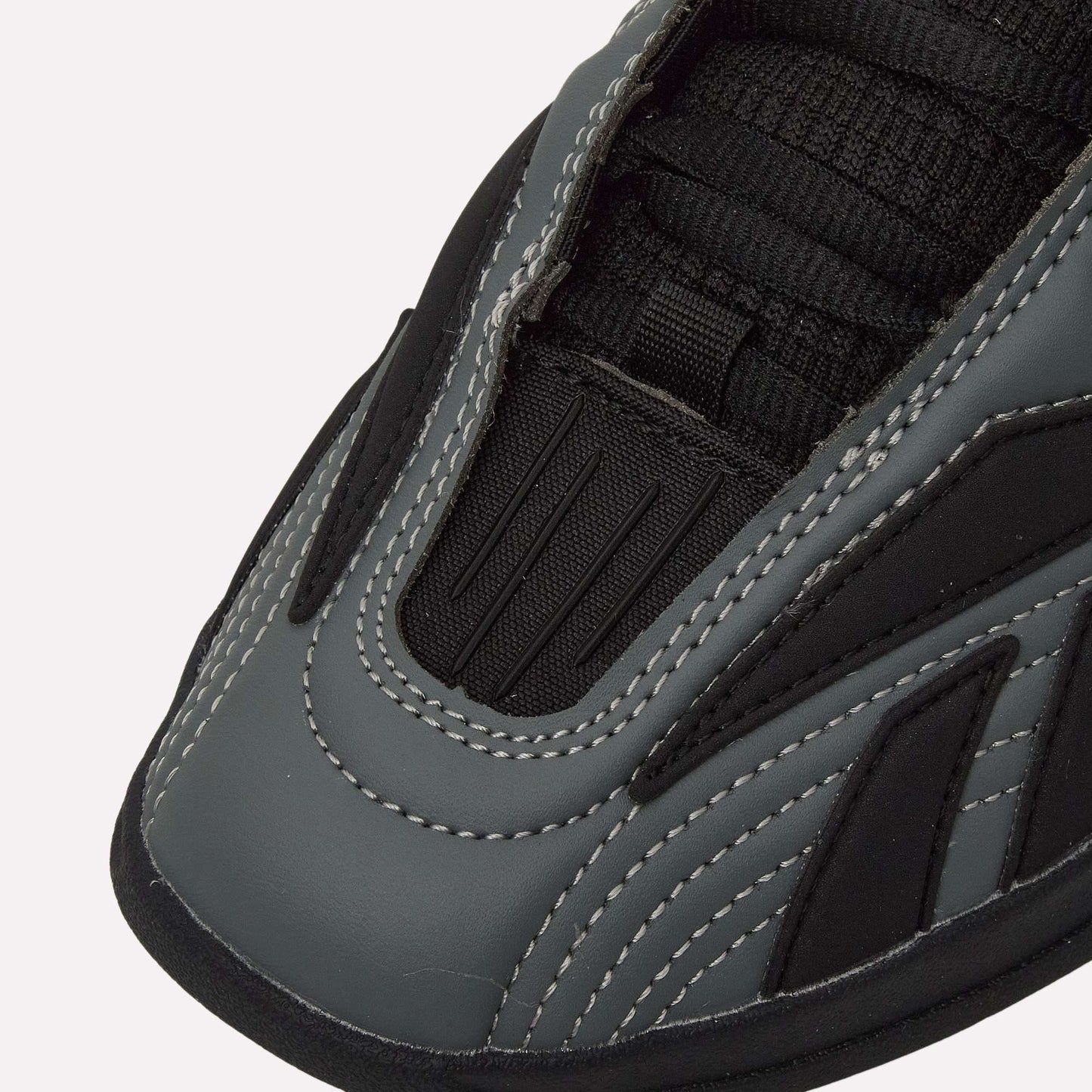 Close-up of the toe area of Reebok Hammer Pro LTD Shoes, showcasing gray and black faux leather panels, white stitching, and black mesh near the laces for a modern, sporty look.