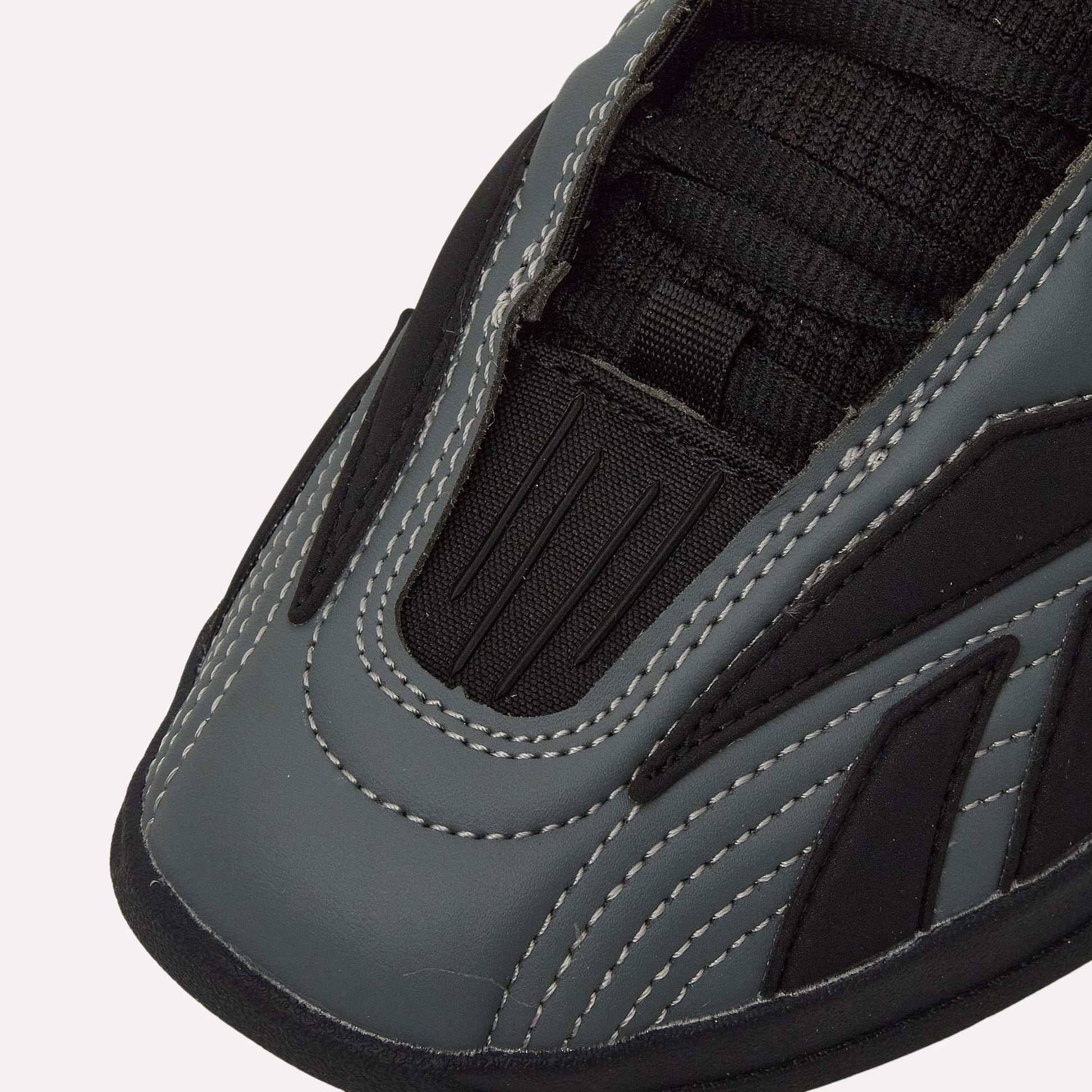 Close-up of the toe area of Reebok Hammer Pro LTD Shoes, showcasing gray and black faux leather panels, white stitching, and black mesh near the laces for a modern, sporty look.