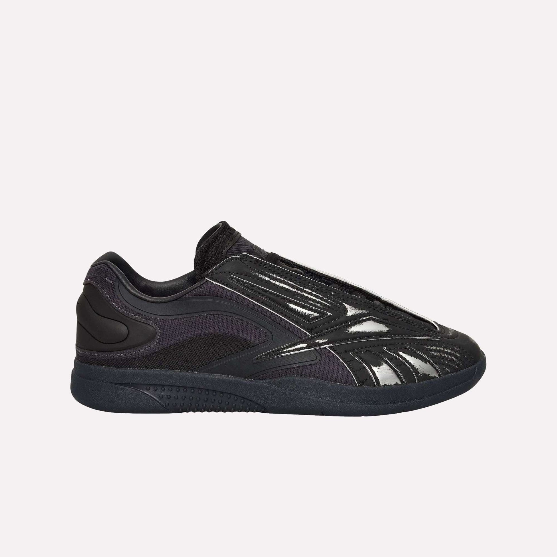 A black Reebok Hammer Pro LTD Shoe with a glossy, textured faux leather upper, mesh and synthetic overlays, and a durable rubber sole, shown in side profile on a white background.