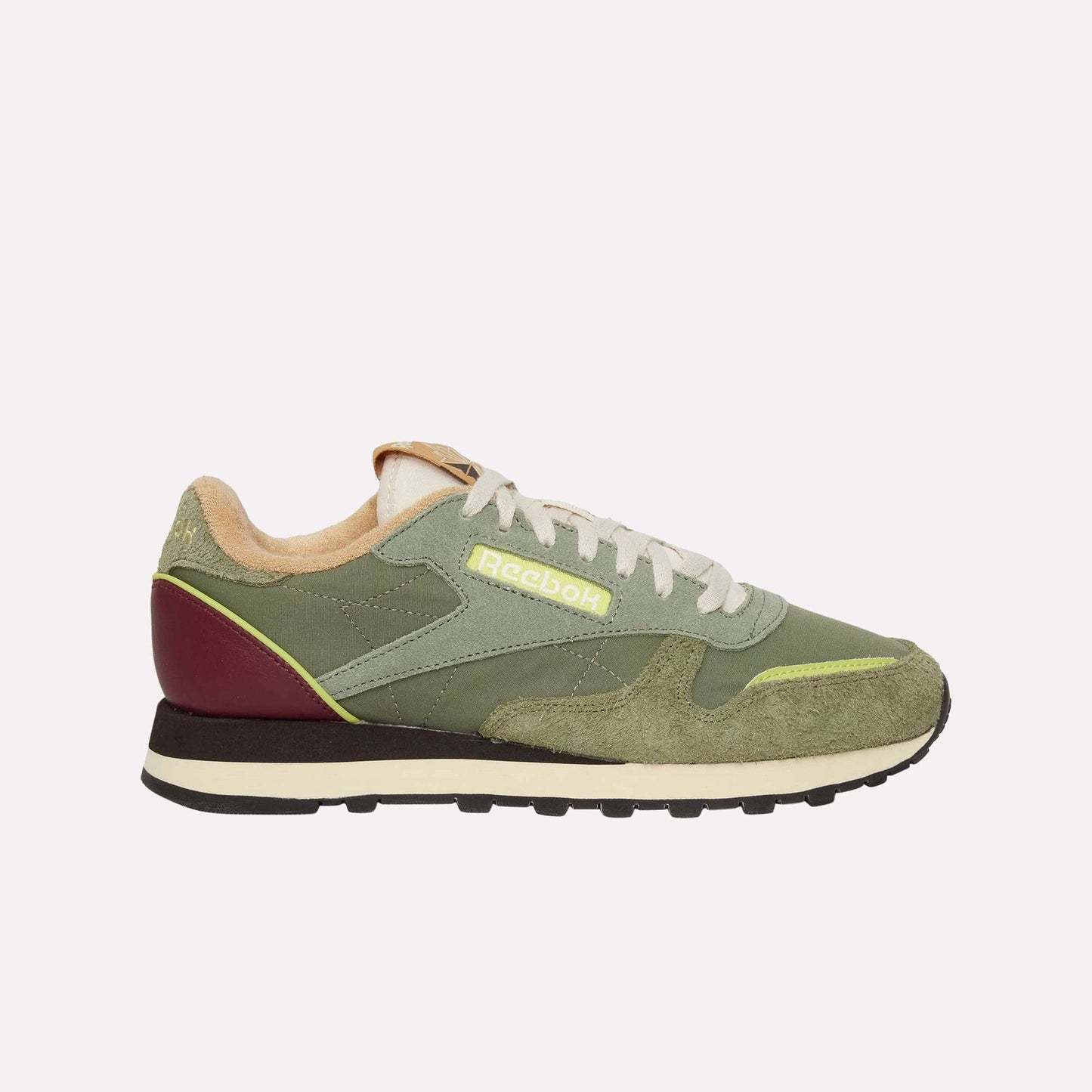 The Reebok Classic Leather Premium LTD Shoes in green feature suede and leather panels, beige laces, a maroon heel accent, and a cream and black sole. A classic silhouette highlights the yellow Reebok logo on the side.