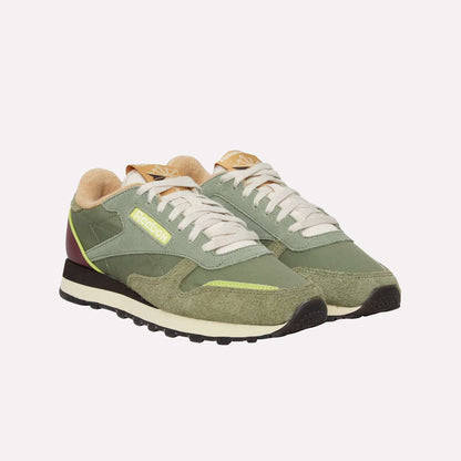 A pair of Reebok Classic Leather Premium LTD Shoes in green with cream laces, suede and leather accents, yellow logos, and black-brown outsoles are displayed side by side on a white background.