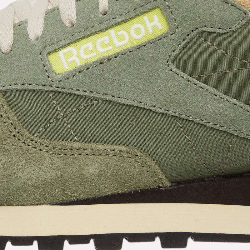 Close-up of the Reebok Classic Leather Premium LTD Shoes in green, highlighting suede and fabric textures, beige midsole, and a yellow patch with white Reebok logo—ideal for retro sneaker enthusiasts and lovers of classic silhouettes.