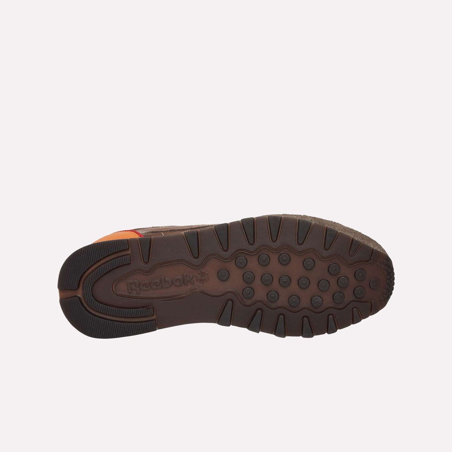 The image displays the bottom of a brown Reebok Classic Leather Premium LTD Shoe, highlighting its textured rubber sole with circular grips and the embossed Reebok logo near the heel—reflecting its signature classic design.