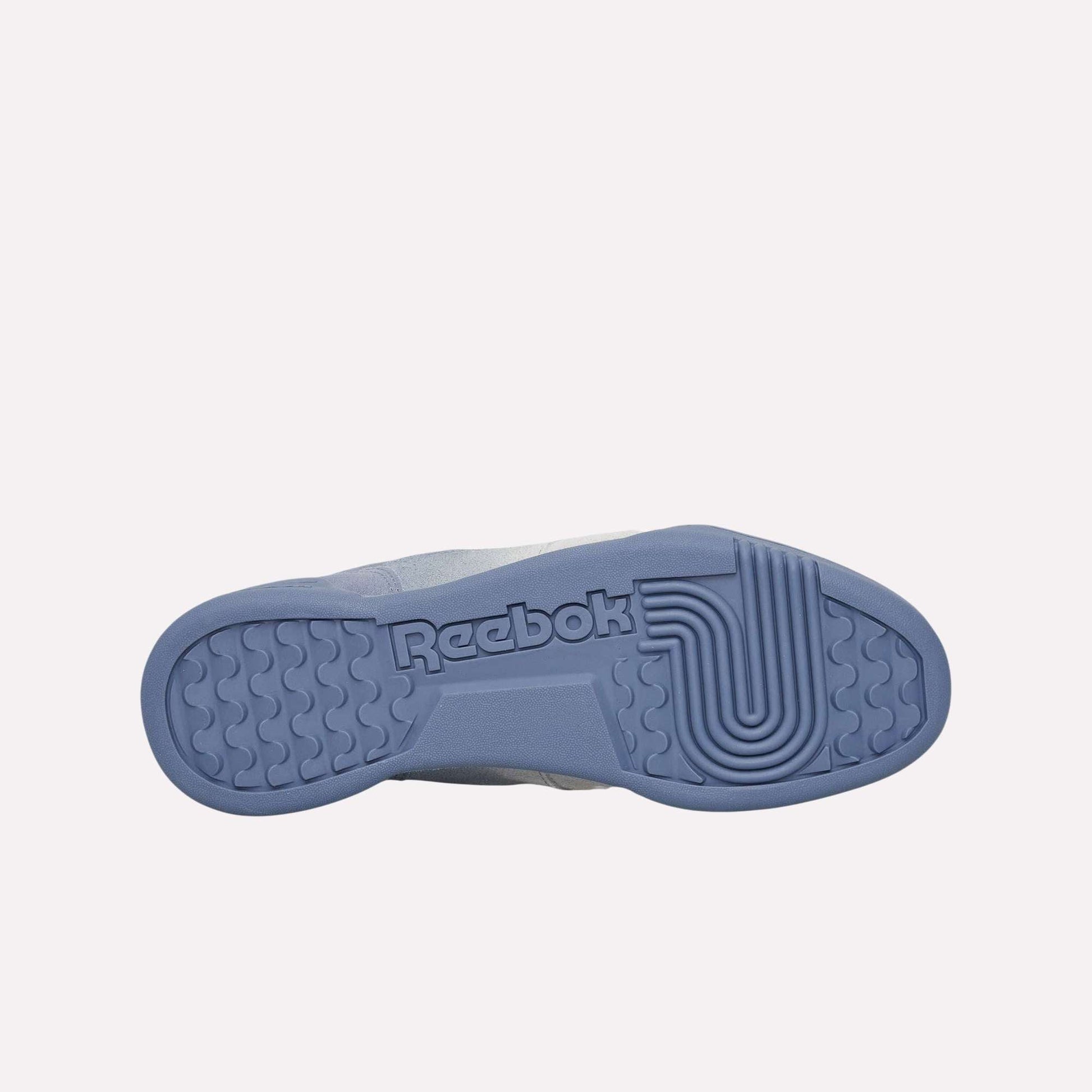 Against a light blue background, the textured sole of the Reebok Workout Plus Og Shoes is displayed, featuring the Reebok logo and reflecting the classic retro silhouette of these sneakers.