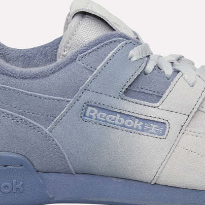 Close-up of light blue and white Reebok Workout Plus Og Shoes with visible side logo, laces, and stitching. The classic retro silhouette stands out against a light blue background.