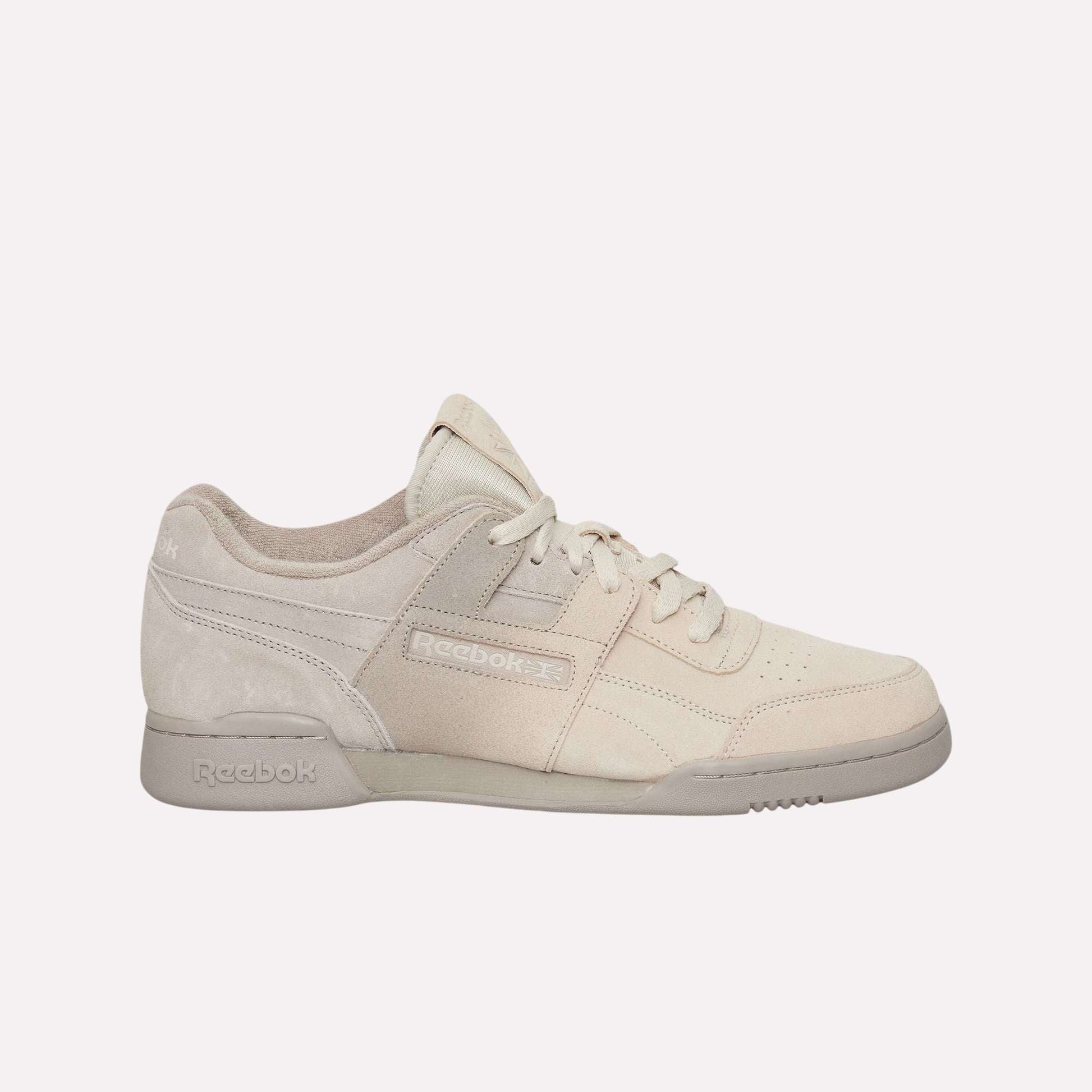 The Reebok Workout Plus Og Shoes feature a beige suede upper, tonal laces, and an off-white sole, highlighting their classic silhouette against a light blue background.