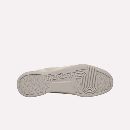 The image displays the sole of a Reebok Workout Plus OG shoe, showcasing the Reebok logo and distinctive textured details, set against a light blue background that highlights its classic retro silhouette.