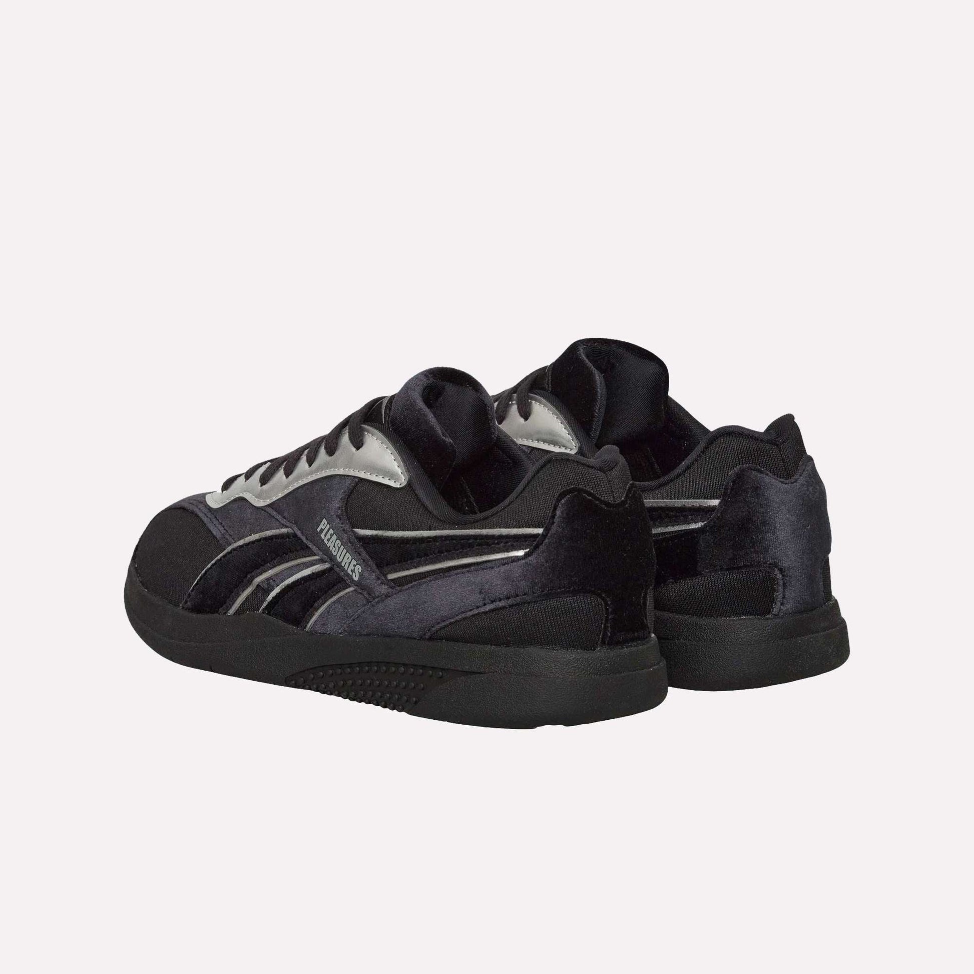 The Reebok Pleasures Hammer Street Shoes, black and silver with a velvet upper and black soles, are displayed from back and side angles against a light blue background.