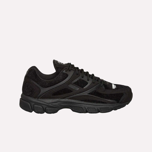 The Reebok Pleasures Premier Trinity KFS Shoes feature a black athletic design with mesh and suede details, black laces, a textured rubber sole, and subtle Reebok branding. Displayed on a light blue background.
