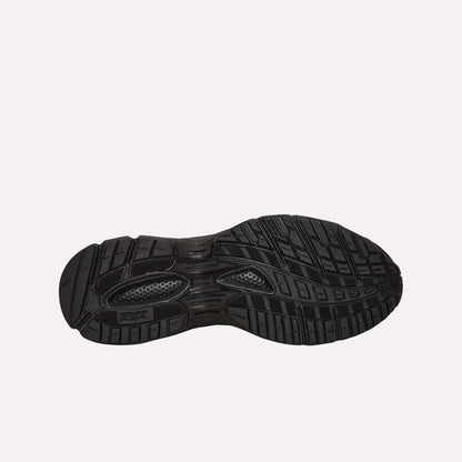 The Reebok Pleasures Premier Trinity KFS Shoes feature a black rubber sole with textured tread for grip, grooves, and raised sections for traction. Photographed on a light blue background, this design is part of a Pleasures collaboration.