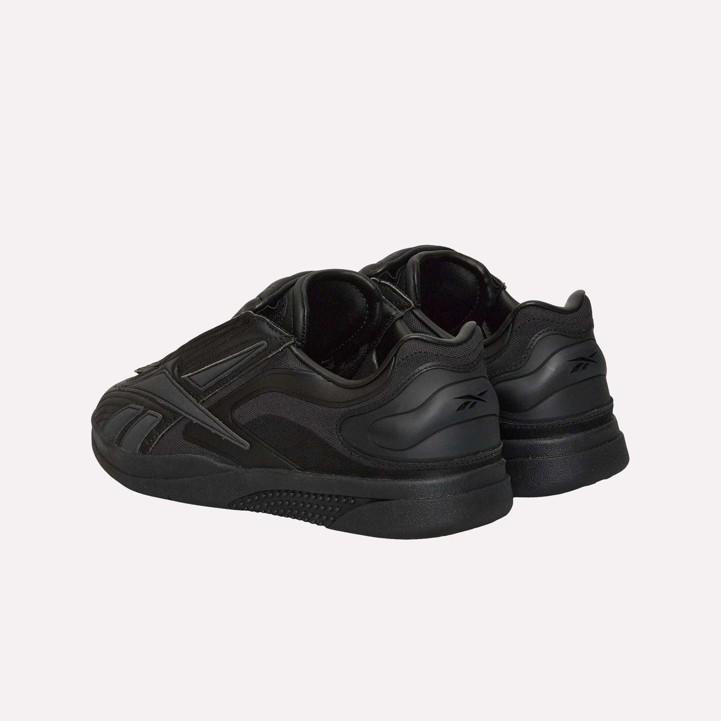 The Reebok Hammer Pro Ltd sneakers, shown in black from a rear side angle, feature a suede upper, low-cut silhouette, durable rubber sole, and subtle branding on the heel tabs.