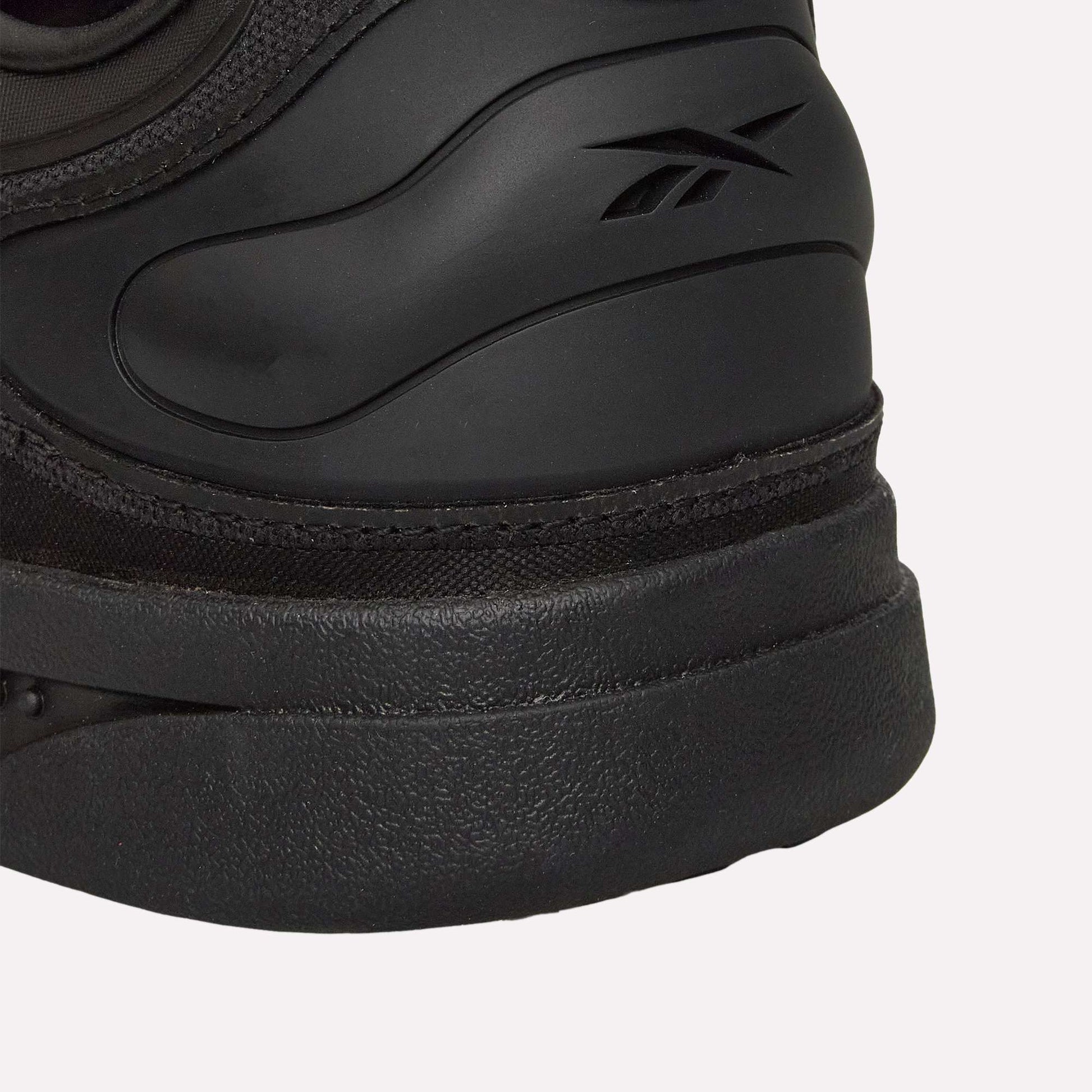Close-up of the heel on a Reebok Hammer Pro Ltd sneaker, showing the embossed Reebok logo on the side. The shoe features a smooth upper and durable rubber sole.