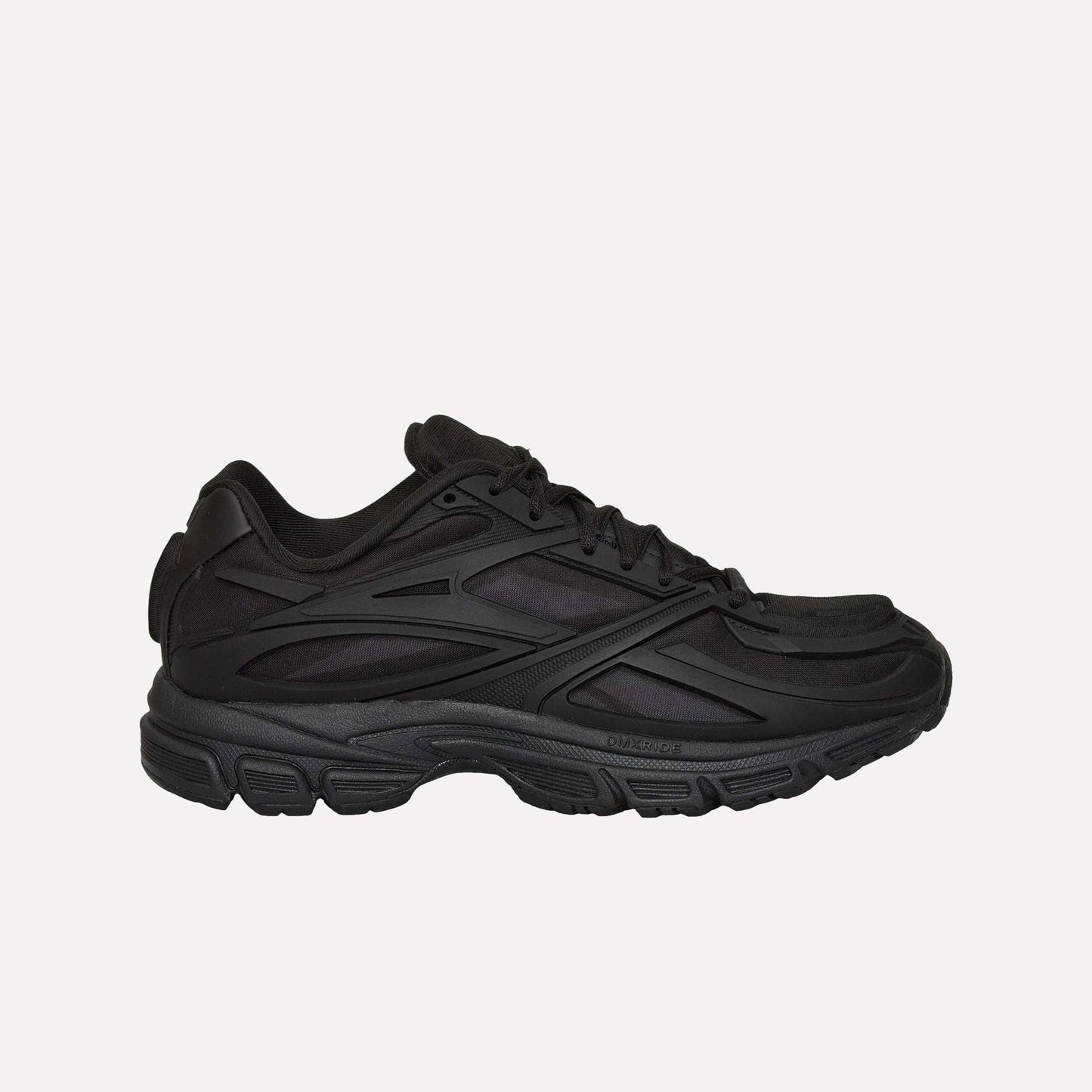 A black Reebok Premier Road Modern running shoe with a chunky sole and layered, textured side details is shown from the left against a white background.