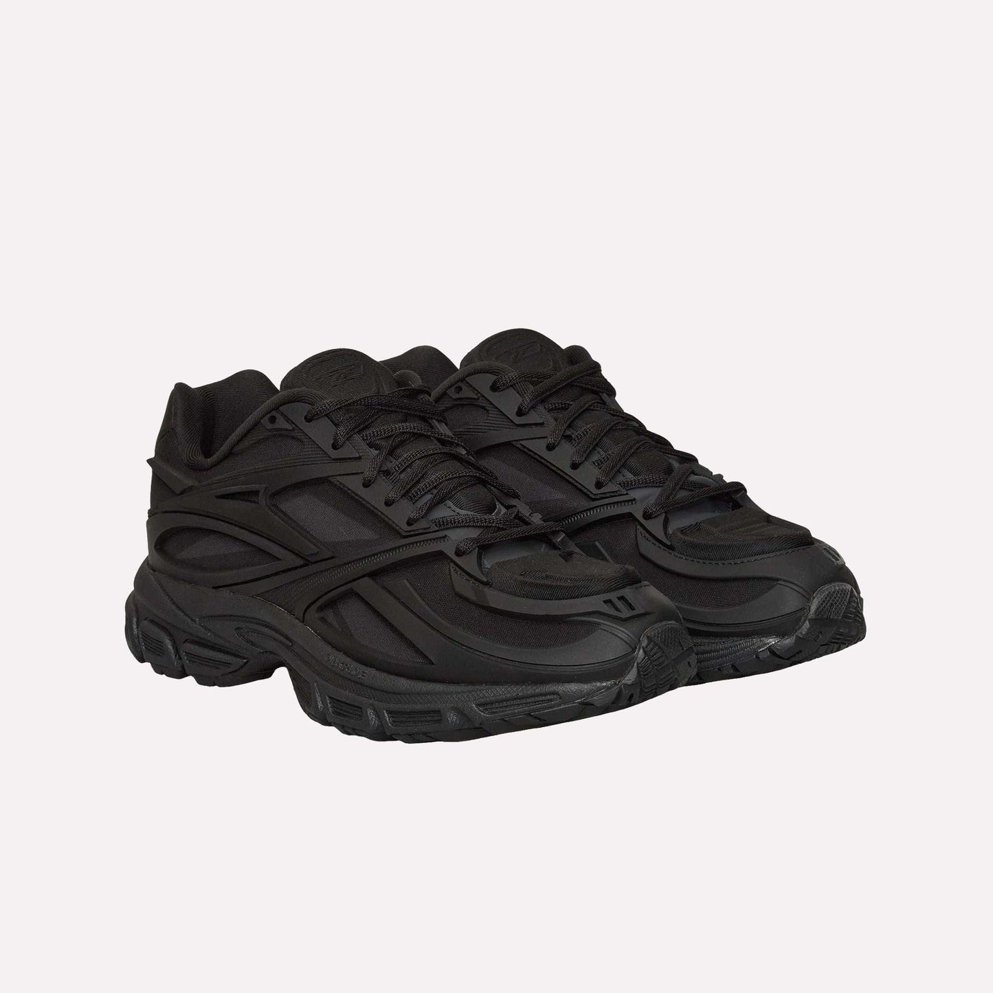 A pair of Reebok Premier Road Modern running shoes in all-black with textured soles, layered panels, and lace-up fronts, displayed side by side on a plain white background.