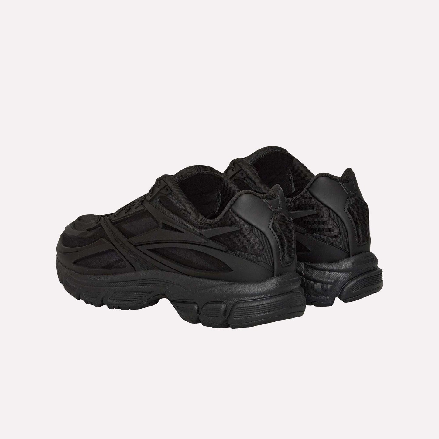A pair of Reebok Premier Road Modern sneakers are shown from the heel, highlighting their chunky soles, dual-density midsole, and sleek design inspired by archival running shoe elements.