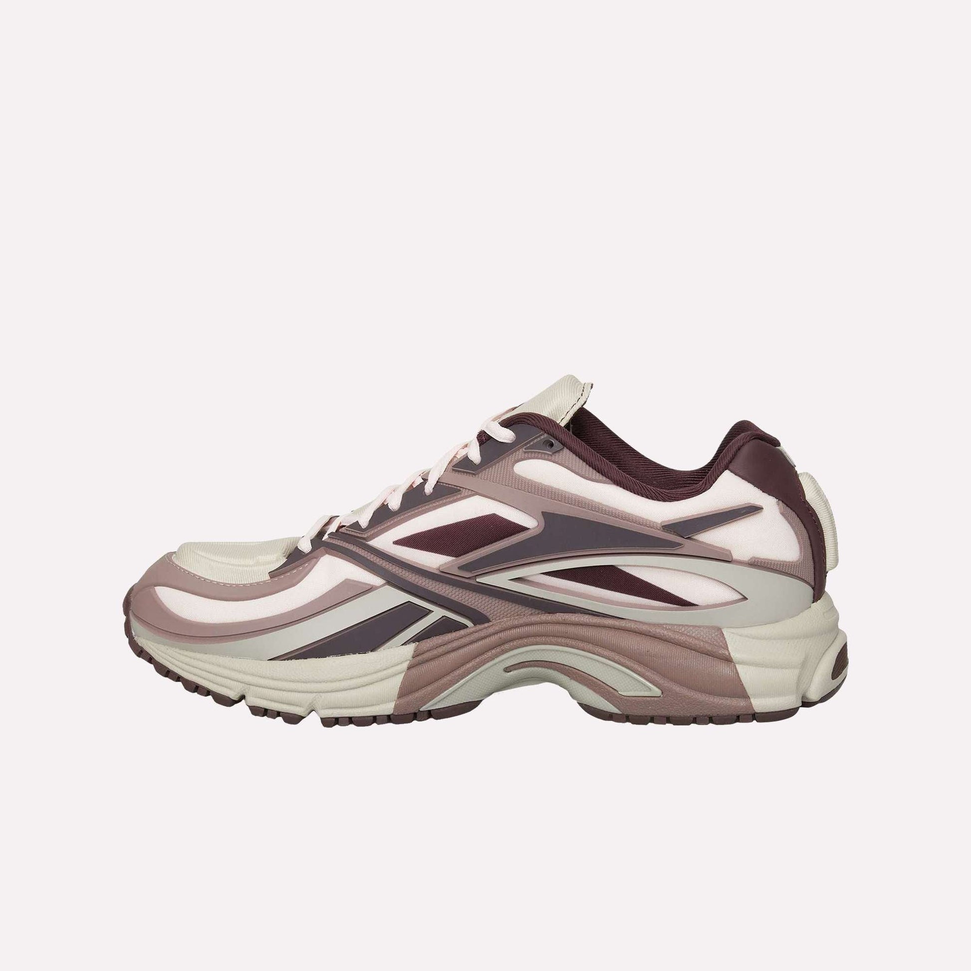 The Reebok Premier Road Modern is a stylish sneaker in cream, mauve, and dark purple, featuring layered details, a wavy sole with dual-density midsole, shown from the side on a white background.