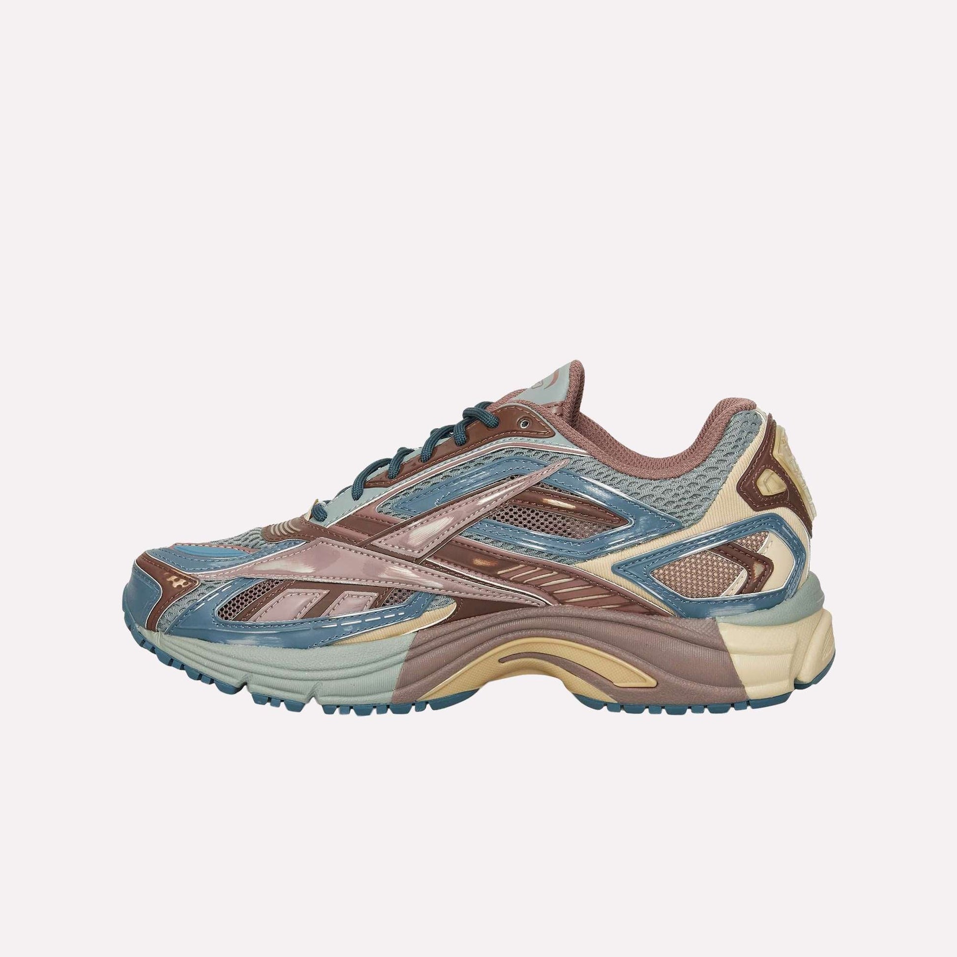 A side view of the Reebok Premier Road Ultra sneaker shows blue, brown, beige, and tan accents with a mesh and synthetic upper, detailed panels, dual-density midsole, and a textured rubber sole.