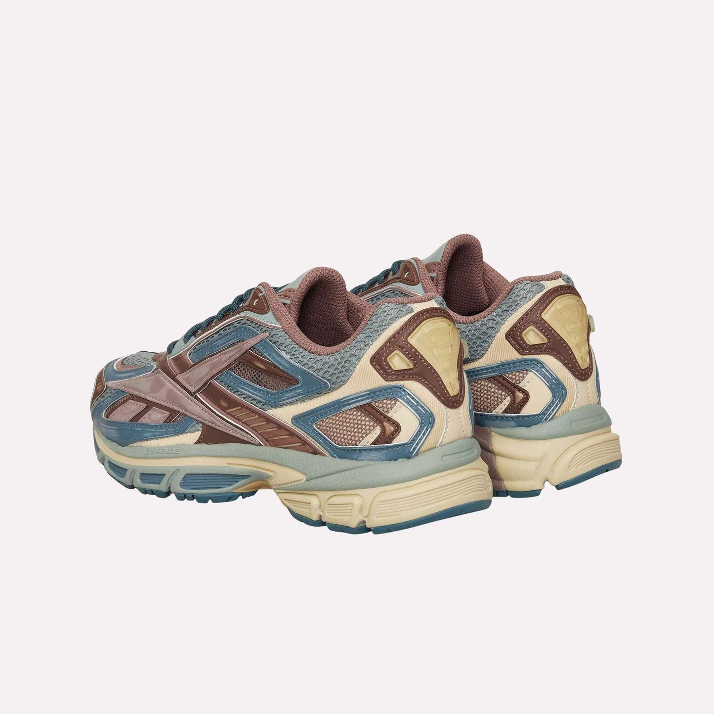 The Reebok Premier Road Ultra sneakers in blue, brown, beige, and gray are shown from the back and side on a white background. They feature a mesh upper, textured accents, thick soles, and a dual-density midsole.