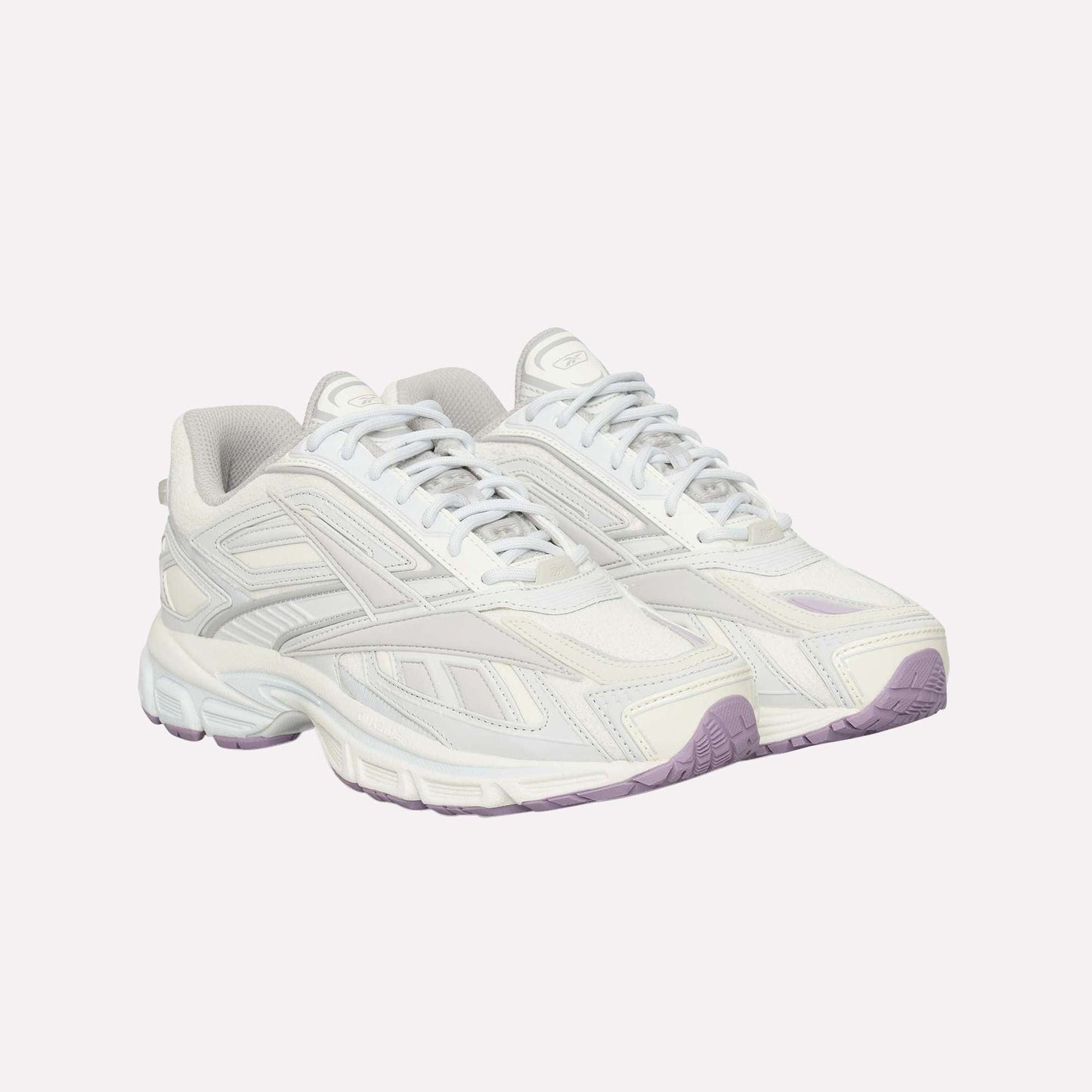 The Reebok Premier Road Ultra is a pair of white athletic sneakers with light grey and off-white accents, chunky soles, a dual-density midsole, light purple outsoles, and a modern sporty lace-up design.