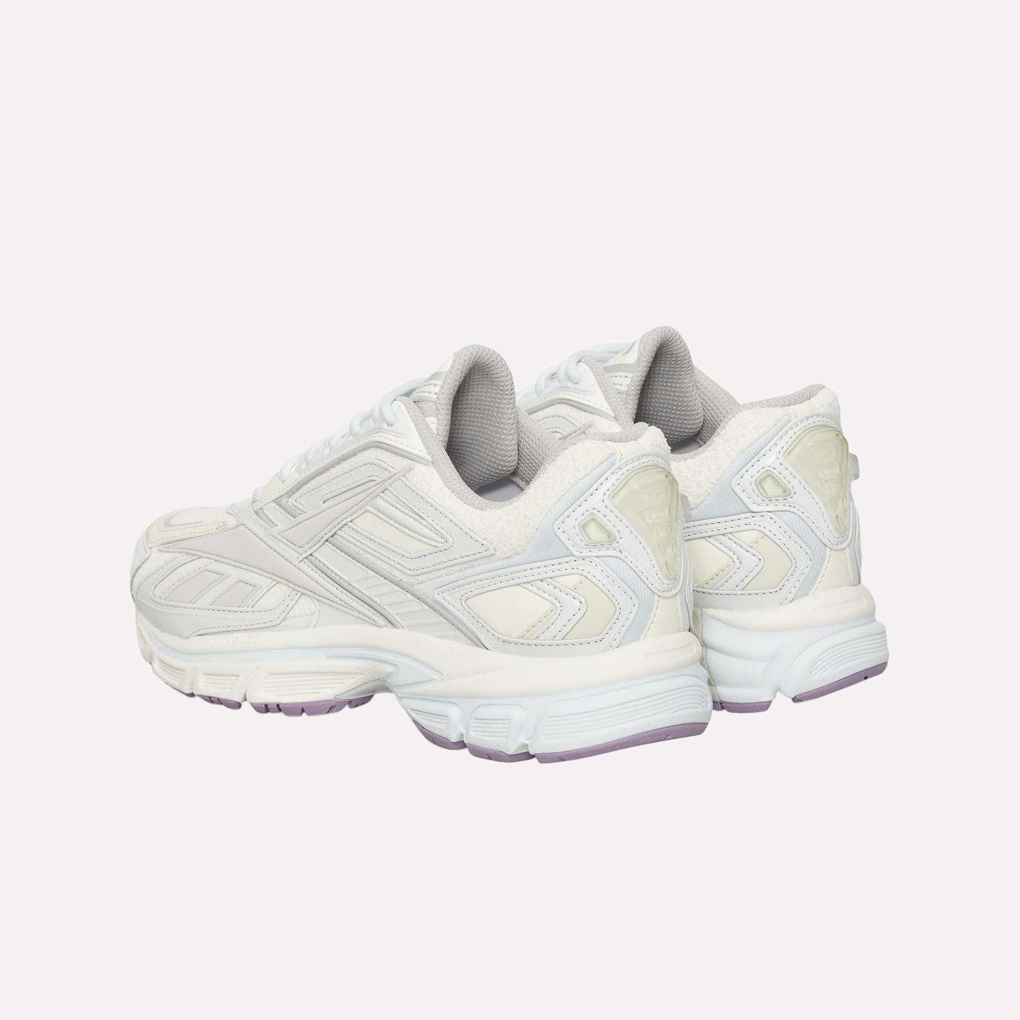 A pair of white Reebok Premier Road Ultra sneakers with light gray and off-white accents, viewed from the rear angle. Features include textured panels, a dual-density midsole, thick soles, and pale purple detailing on the outsole.