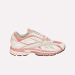 The Reebok Premier Road Ultra, a pink and white sneaker with suede and mesh details, dual-density midsole, chunky sole, and white laces, is shown against a plain white background.